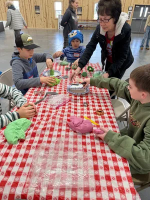 Youth working on arts and crafts at a table with colorful play dough and supplies